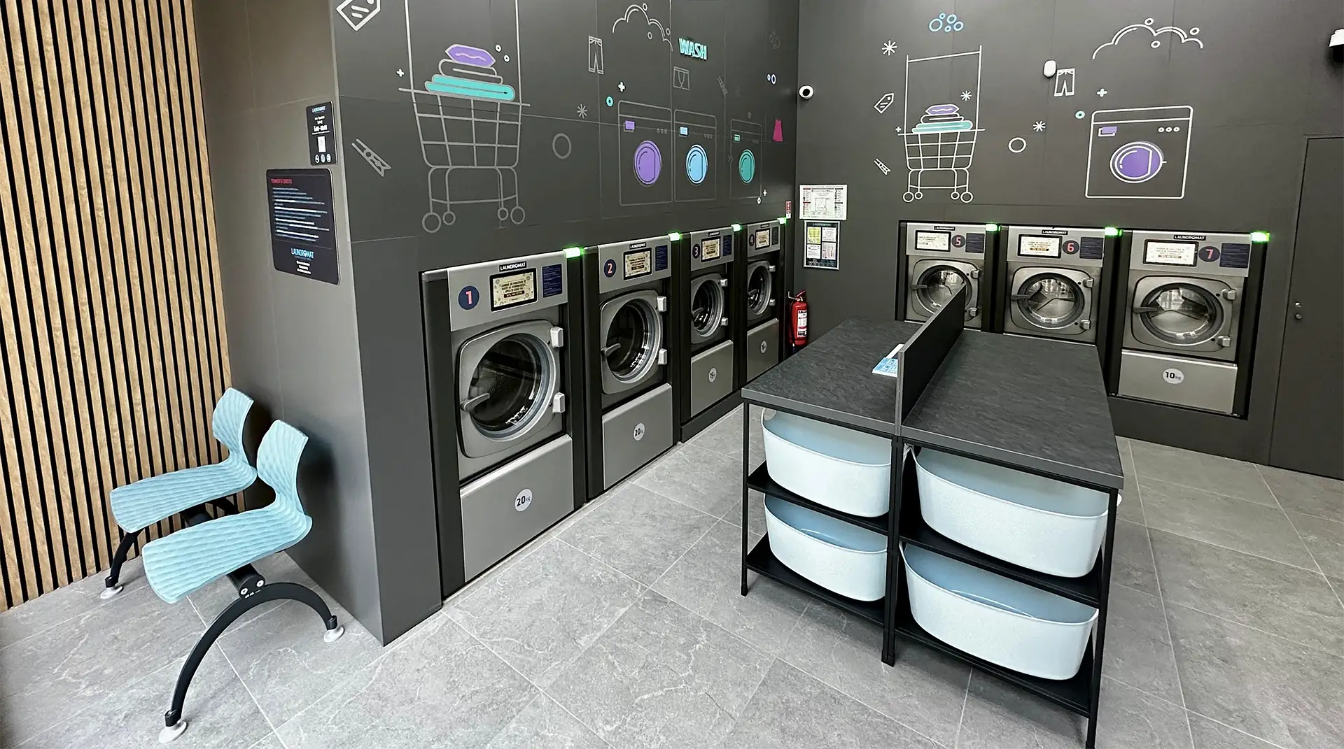 Store view of washers and the board showing self service laundry prices.